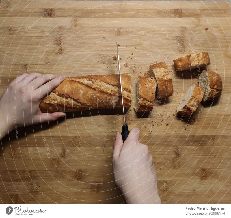 Person, die Brot auf einem Holzbrett schneidet Küche Essen zubereiten Tisch backen Messer Bäcker Hand Koch Speiselokal geschnitten traditionell lecker