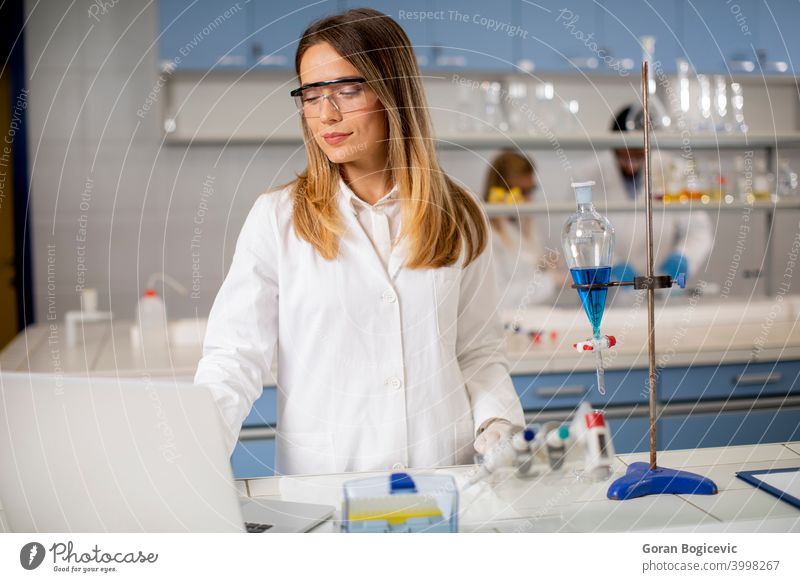 Weibliche Forscherin in weißem Laborkittel und Schutzmaske bei der Arbeit mit Laptop im Labor Analysieren Hintergrund Biografie Chemikalie Chemiker Klinik