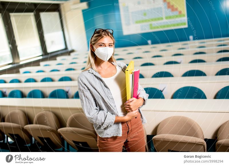 Weiblicher Student, der eine medizinische Gesichtsschutzmaske zum Schutz vor Viren trägt, steht im Hörsaal schulisch schön Kaukasier Hochschule Konzept Korona