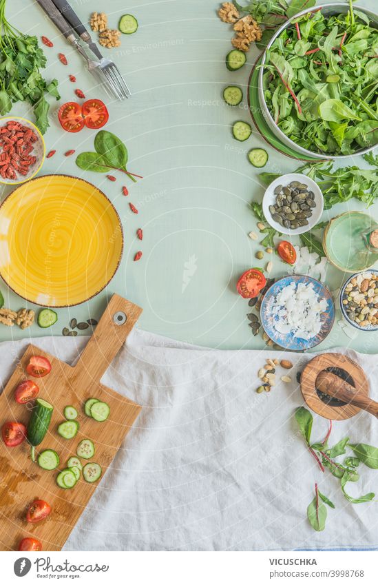 Verschiedene gesunde Salatzutaten auf hellgrünem Küchentisch-Hintergrund. Ansicht von oben. Gesundes Mittagessen Vorbereitung, Rahmen verschiedene Gesundheit