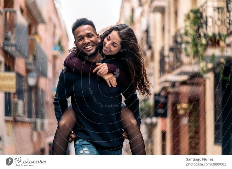 Glücklich Interracial Pärchen Tun Huckepack spielerisch in die Kamera schauen Vorderansicht interrassisches Paar Partnerschaft Madrid Straßen im Freien