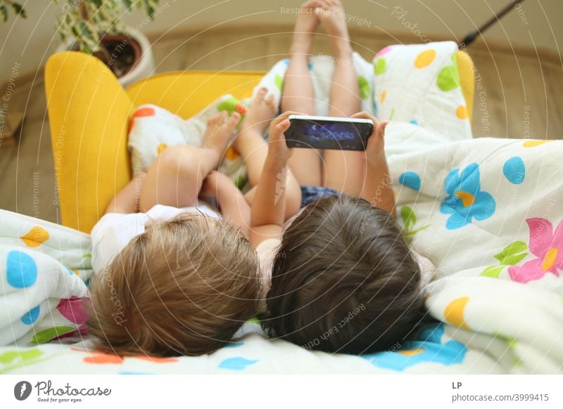 Kinder, die sich in einen Sessel setzen und auf das Telefon schauen Mobiltechnologie Blick Aktivität spielen Daten starren Menschen farbenfroh Farbe attraktiv