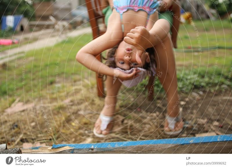 glückliches Mädchen, das auf den Beinen ihrer Mutter sitzend das Zeichen ok /like zeigt Erholung überraschend überrascht Mitteilung Körpersprache Witze