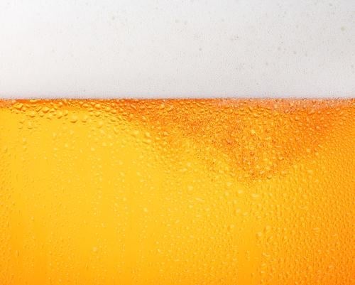 Nahaufnahme des Hintergrunds von Bier mit Blasen im Glas Bierschaum Gießen frostig frisch Lagerbier Tropfen Seite Ansicht tiefstehend Winkel Textur Becher groß