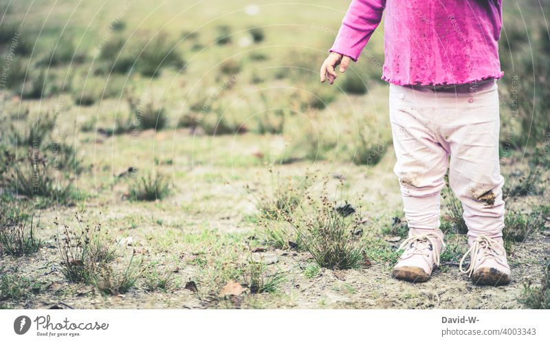 Kind mit schmutzigen Klamotten draußen in der Natur alleine Kleidung dreckig spielen Kindheit Mädchen eingesaut anonym