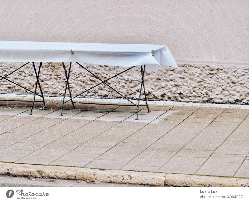 Ein leerer Tisch auf dem Bürgersteig wartet vergeblich auf Gäste... verlassen Tischtuch weiß Stadt Einsamkeit warten niemand Straße urban Menschenleer Mauer