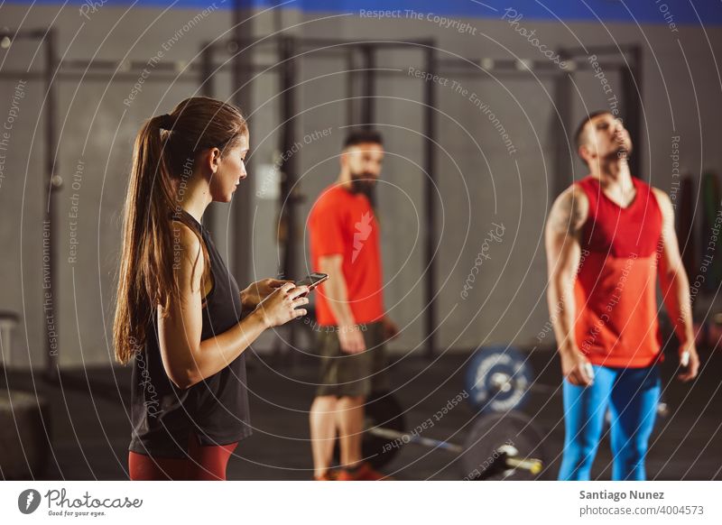 Frau schaut im Fitnessstudio auf ihr Smartphone. Crossfit Funktionstraining Gesundheit Sport Training Übung Lifestyle Kunstturnen Gerät Raum vereinzelt