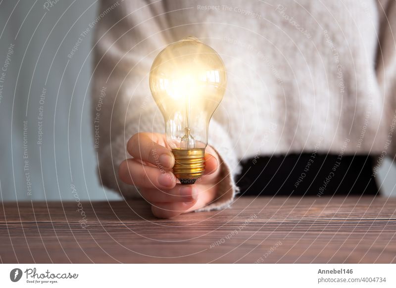 Weibliche Hand hält eine leuchtende Glühbirne, große Idee, Innovation und Inspiration, Business-Konzept Hintergrund Licht Knolle Energie Lampe hell Elektrizität