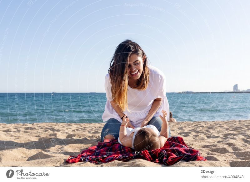 Lächelnde Mutter spielt mit Neugeborenen auf Strandtuch liegend Baby neugeboren Liebe Lügen Familie Fröhlichkeit Frau Person Handtuch Lachen Sand Sonnenlicht