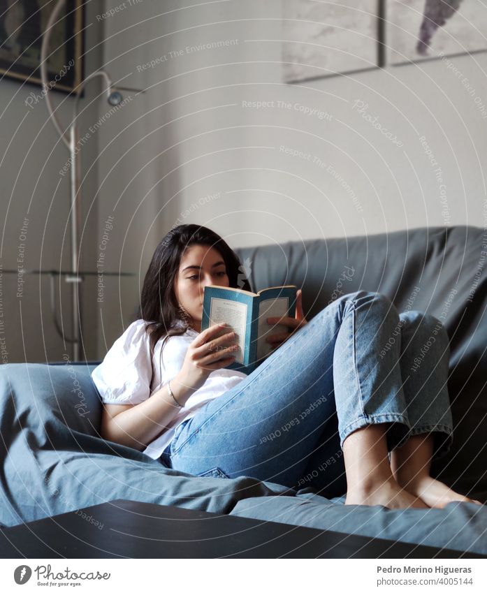 Frau lesend auf einem Sofa in einem Haus heimwärts Freizeit Sitzen bequem Wohnzimmer Kaukasier Lifestyle brünett im Innenbereich häusliches Leben