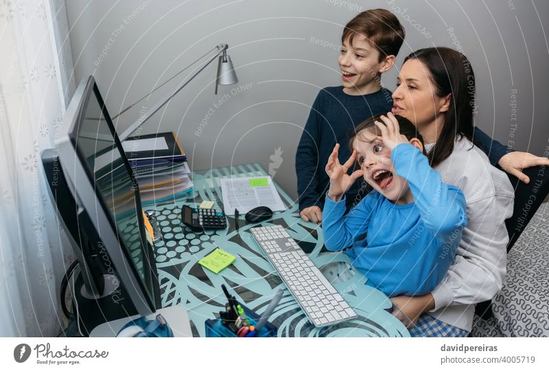 Familie spricht per Videoanruf, während das Mädchen eine Grimasse zieht Mutter Kinder Spaß Grimassen schneiden Computer Coronavirus Quarantäne sprechend
