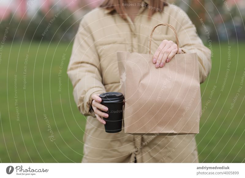 Tasse zum Mitnehmen mit Kaffee, Mock-up für Identität Branding. Nahaufnahme von Papiertüte und Pappbecher in weiblicher Hand.Junge Frau trägt Einkaufstaschen und Kaffee.
