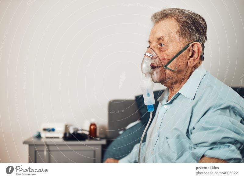 Älterer Mann beim Einatmen der Atemwege und der Lunge bei der Anwendung von Medikamenten. Behandlung mit Covid-19 oder Coronavirus. Mann atmet durch Gesichtsmaske mit Vernebler