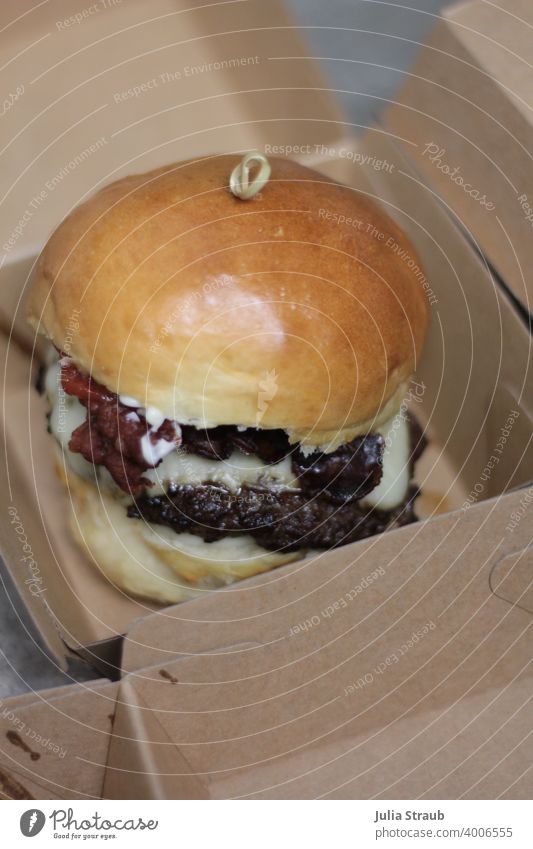 hausgemachter Cheeseburger in Kraftpapier verpackungsbox Burgerbrötchen Burgerlove cheese Käse Patty Fleisch Rinderhack glänzend Speck lecker fluffig Fastfood