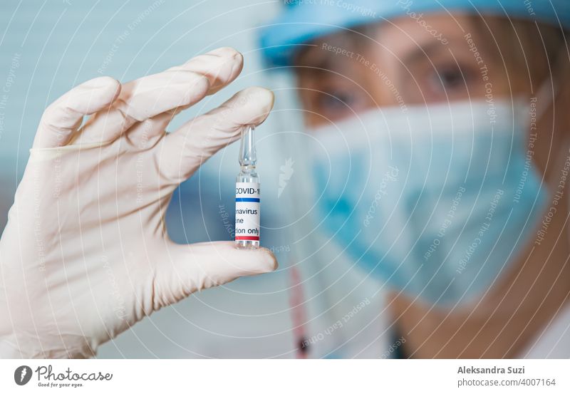 Ärztin mit OP-Maske und in Handschuhen hält Impfstoffampulle und Spritze. Impfung während der COVID-19-Pandemie Arme Pflege Klinik Coronavirus covid-19 Kur