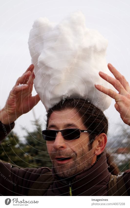 Portrait eines bärtigen Mannes mit dunkler Brille balanciert einen Riesen Schneeball auf seinem Kopf balancieren bart brille eis erwachsen fröhlichkeit gefroren