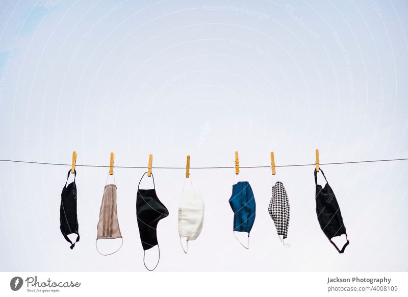 Viele Schutzmasken hängen am Seil COVID Mundschutz Pandemie waschbar Himmel In einer Reihe Textfreiraum Coronavirus krank Kleiderspin Textil erhängen