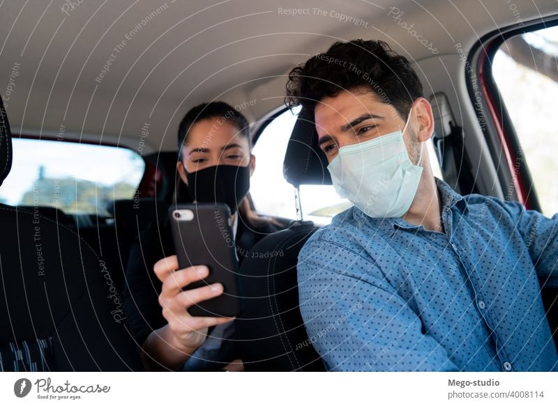 Frau zeigt dem Taxifahrer etwas auf dem Telefon. Mann Geschäftsmann Mobile PKW Gesicht Mundschutz Transport Kabine männlich eine Porträt Erwachsener