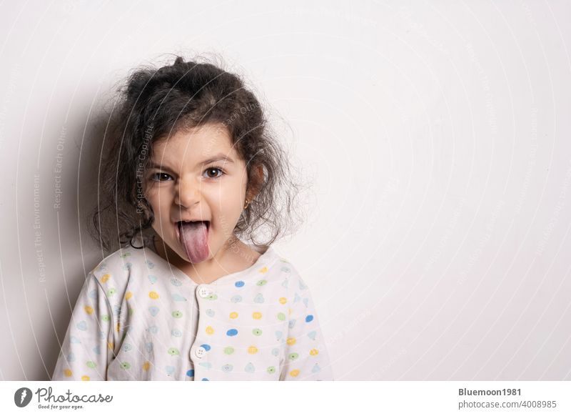 Kleines Mädchen Porträt mit außerhalb Zunge Mädchen zeigt Zunge lustige Haltung kleines Mädchen Mund zwei Jahre alt Spaß spielen Gesundheit Oberkörper Mode