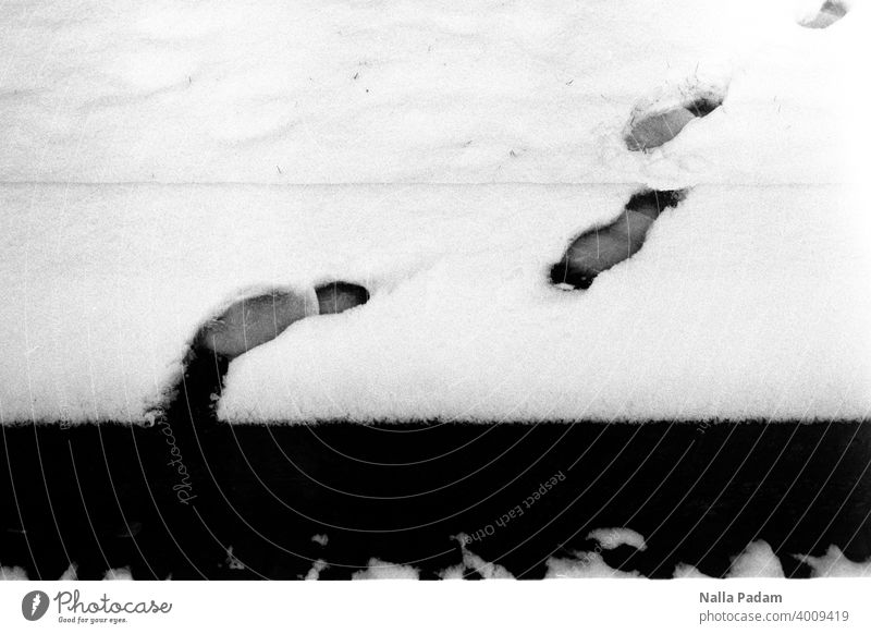 Fußspuren im Schnee analog Analogfoto Schwarzweißfoto schwarzweiß Spur Fußabdruck Winter Abgrund Ende Mauer Schritt kalt Außenaufnahme Blick zurück Beweis glatt