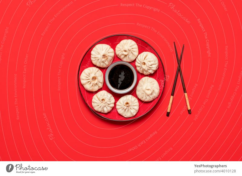 Baozi-Knödel auf rotem Teller mit Sojasauce. Gedämpfte Bao-Knödel, flach gelegt asiatisch Bapao Brötchen Chinesisch chinesisches Essen Essstäbchen