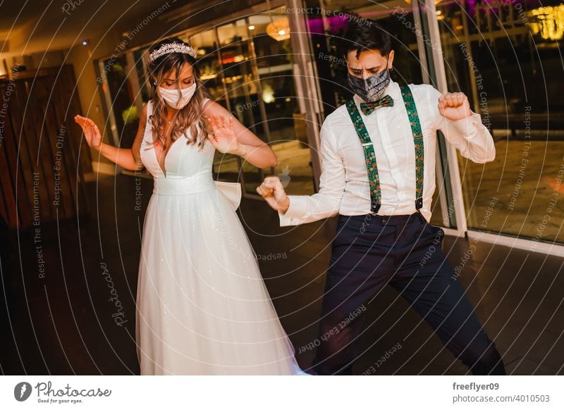Junges Paar mit chirurgischen Masken tanzen auf ihrer Hochzeit Heirat Engagement Braut COVID Gesichtsmaske Operationsmaske Party sicher Coronavirus COVID19