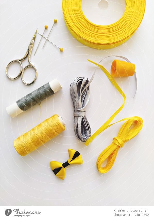 Flat Lay mit Nähzeug und Nähzubehör in den Trendfarben leuchtendes Gelb und ultimatives Grauband Zubehör Garnspulen kariert Konzept Handwerk diy