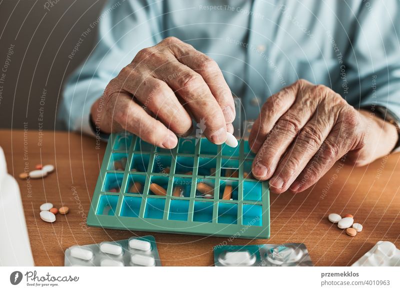 Senior Mann organisiert seine Medikamente in Pillenspender. Senior Mann nimmt Pillen aus Box Tablette Krankheit Spender geduldig Verschreibung medizinisch