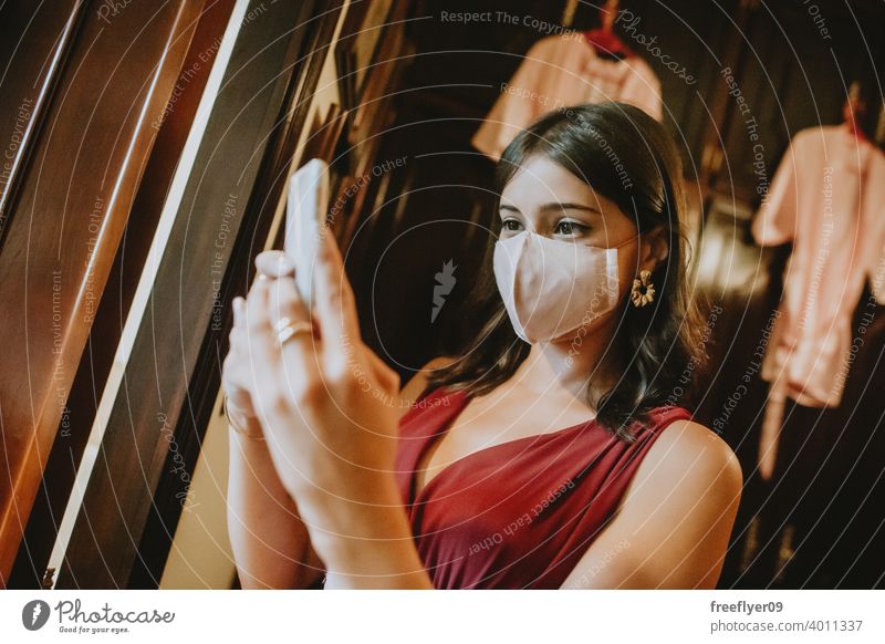 Brautjungfer mit einer chirurgischen Maske, die Fotos mit ihrem Telefon macht Mundschutz Hochzeit Gesicht Gesichtsmaske Operationsmaske Pandemie Menschengruppe