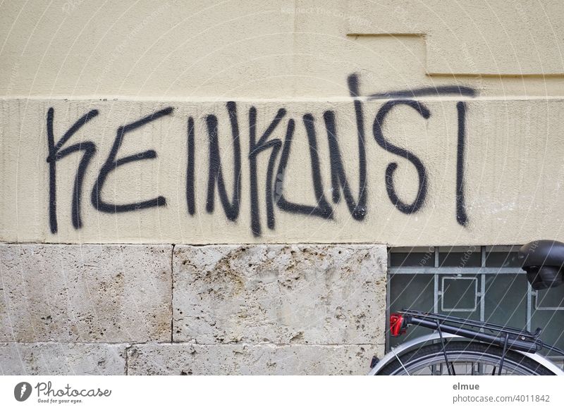 "KEINKUNST" hat jemand in großen schwarzen Buchstaben an die Hausfassade gesprayt / Sprayer / Graffito Keinkunst sprayen Fassade Fahrrad Kleinkunst Wort