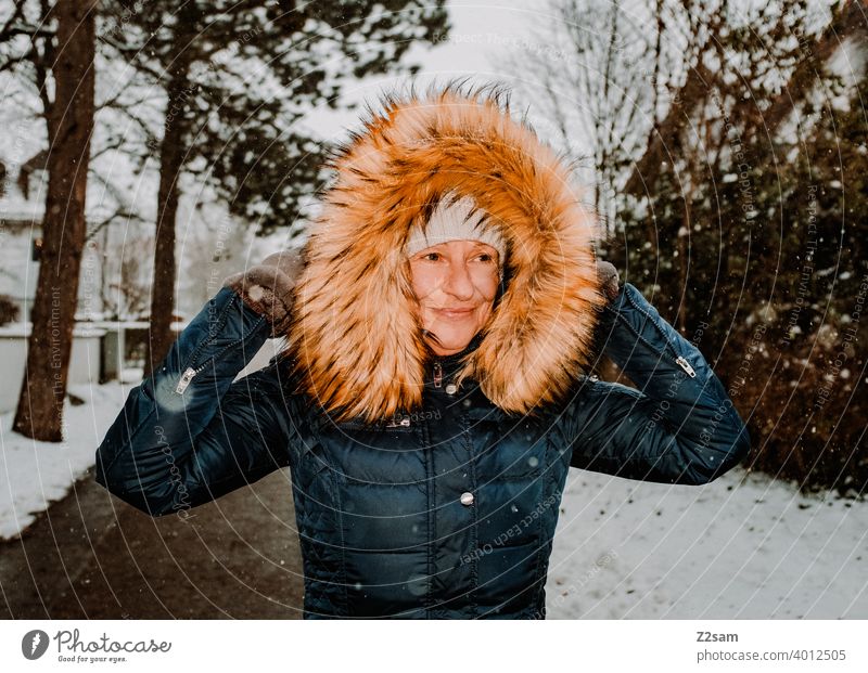 Frau spaziert bei Schneefall durch die Straßen spaziergang Spaziergang Winterspaziergang Kaminsims kunstpelz lachen lächeln Wärme schneefall Schafe Kälte weiss
