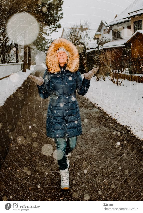 Frau spaziert bei Schneefall durch die Straßen spaziergang Spaziergang Winterspaziergang Kaminsims kunstpelz lachen lächeln Wärme schneefall Schafe Kälte weiss
