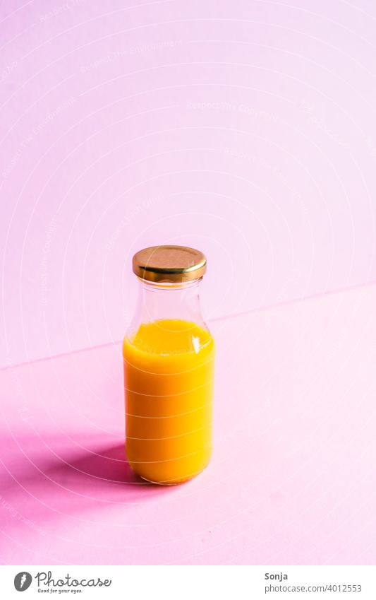 Orangensaft in einer Glasflasche auf einem rosa Hintergrund isoliert Frühstück Farbfoto Gesunde Ernährung Vitamin Vitamin C Foodfotografie Vegane Ernährung