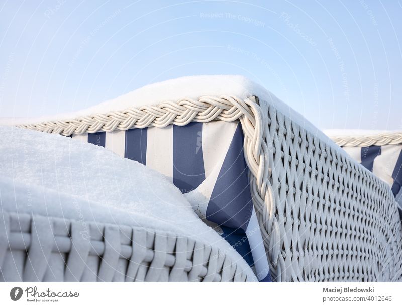Nahaufnahme von überdachten Strandkörben, die mit Schnee bedeckt sind. Weide Stuhl Winter Konzept abschließen Himmel Urlaub blau reisen Tourismus Sonnenbad
