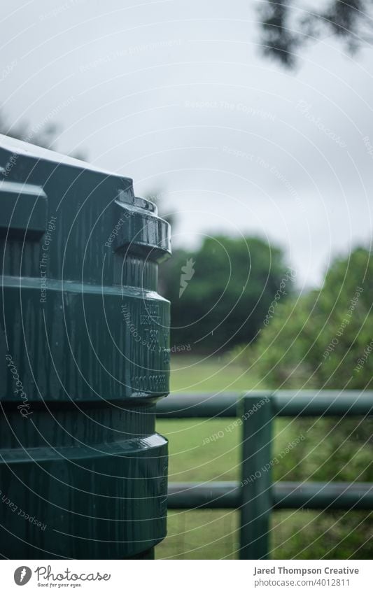 Ein Regenwassertank auf dem Land bekommt eine Dusche. Tank Wasser fluten Unwetter Wolken Australien Dorf Zaun im Freien Natur grün wolkig stürmisch kalt Wetter