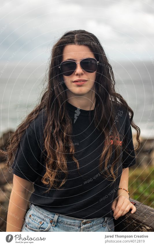Eine junge Frau in der Nähe der Küstenlinie in Port Macquarie, Australien. Frauen Mädchen Teenager 20s Erwachsener lange Haare Behaarung Brille braun schwarz