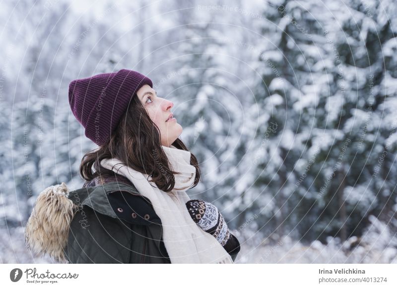 Junges Mädchen, Frau geht in schönen Winterwald unter Bäumen, Tannen, mit Schnee bedeckt. Magnificent Natur und Ansichten. Modisches Bild, Kleidung, Parka, Hut, Handschuhe, Blue Jeans