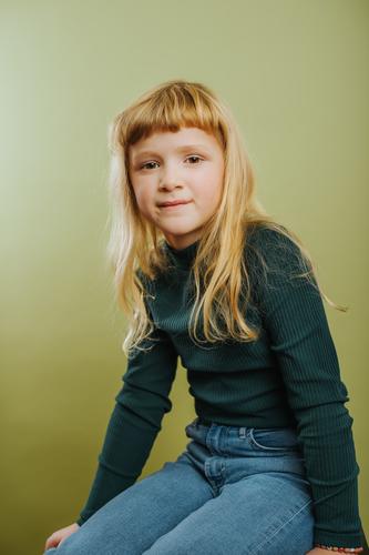 Porträt von niedlichen blonde Mädchen gegen grünen Hintergrund Pony blondes Haar Freizeitkleidung Kind Kindheit farbiger Hintergrund Emotion grüner Hintergrund