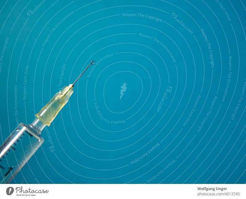Eine Spritze mit Flüssigkeitstropfen auf blauem Hintergrund vereinzelt Korona Nahaufnahme Stoß Impfung kalt Grippe Gesundheit Pflege Medikament Medizin Jena