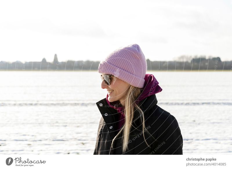 Frau mit Mütze in verschneiter Landschaft kalt Winter Lächeln blond Sonnenbrille hell Porträt Junge Frau Außenaufnahme Schnee Natur Farbfoto Mensch Lifestyle