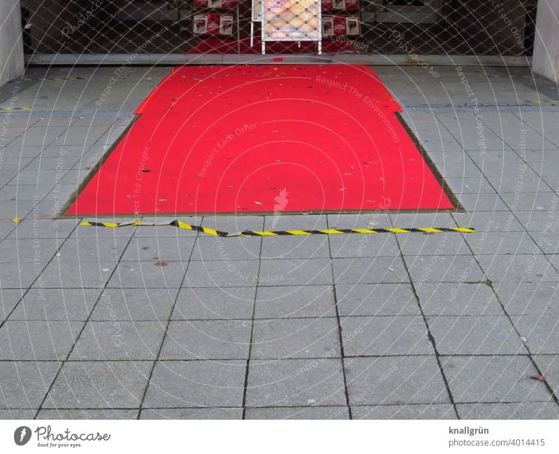 Roter Teppich vor einem geschlossenen Kino Lockdown Markierungslinie Rollgitter rot Außenaufnahme Menschenleer Veranstaltung Tag Empfang Textfreiraum grau