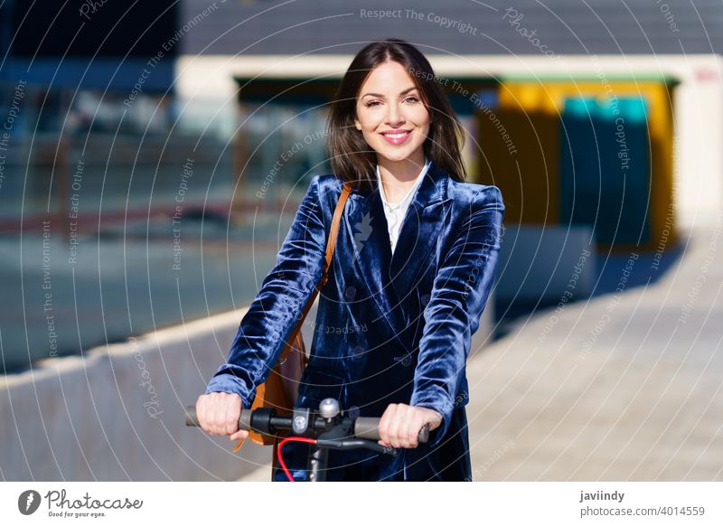 Junge Geschäftsfrau im blauen Anzug benutzt einen Elektroroller. Tretroller Frau elektrisch E-Roller Mädchen urban Fahrzeug Straße Kaukasier