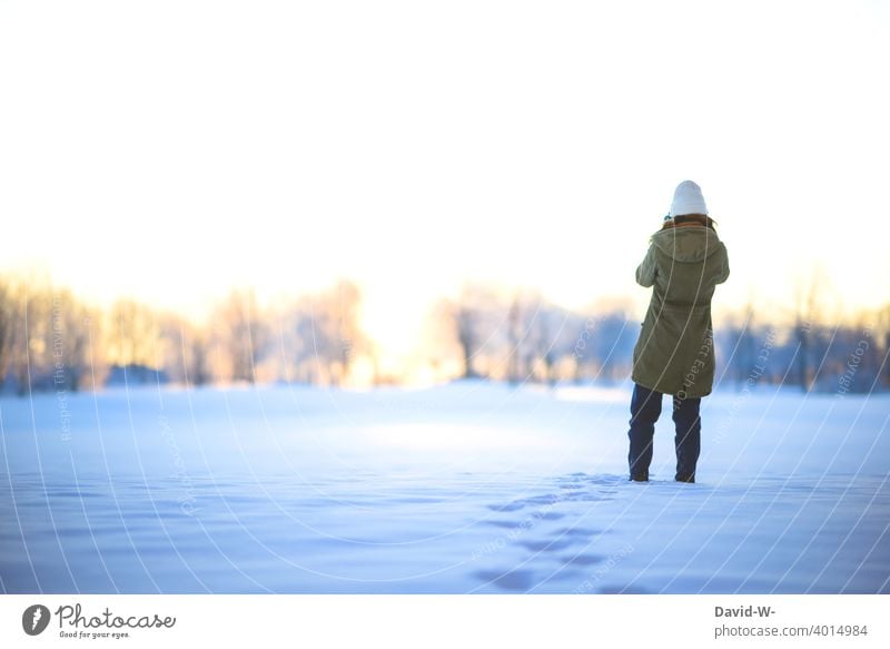 Frau macht an einem schönen Wintertag im Winter einen Spaziergang durch den Schnee Winterzauber Sonnenaufgang Weihnachten winterlich Natur weiß Schneespur