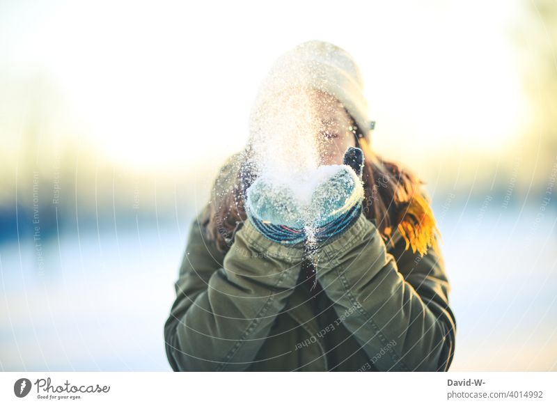 ein schöner Wintertag - Frau pustet Schnee von ihren Händen in die Luft winterlich Winterstimmung Dezember pusten Spaß Freude Wintereinbruch Sonnenlicht
