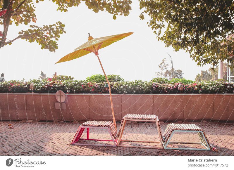 Stühle und ein gelber japanischer Regenschirm an einem Sommertag Japanischer Regenschirm japanischer Stil orientalisches Design Asien Stuhl Garten tropisch
