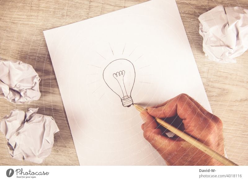 Mann malt eine Glühbirne auf einen Zettel - Konzept / Idee & Einfall Ergebnis Antwort Ehrgeiz Kreativität Lösung Ziel Bildung Bildungswesen Stift Zeichnung