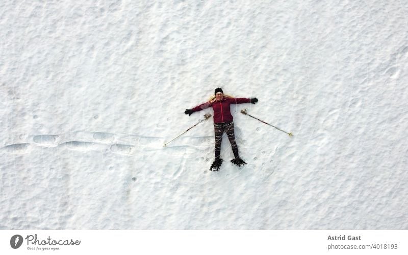 Luftaufnahme mit einer Drohne von einer Schneeschuhläuferin die im Schnee liegt luftaufnahme frau sport winter schnee wintersport schneeschuhlaufen mensch