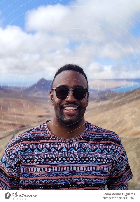 Porträt eines schwarzen Mannes in einer Ansicht von Fuerteventura. vereinzelt Straße Schönheit heiter Typ im Freien Freizeitkleidung Lächeln Person photogen