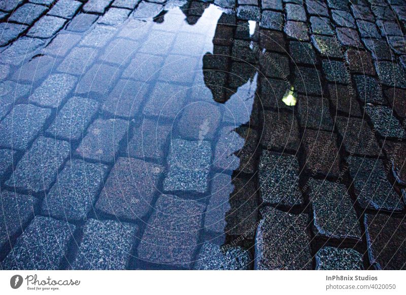 Mann geht auf einer Straße über eine Wasserpfütze Europa Kacheln Perspektive Stock Textur blau Windstille Reflexion & Spiegelung Betrachtungen
