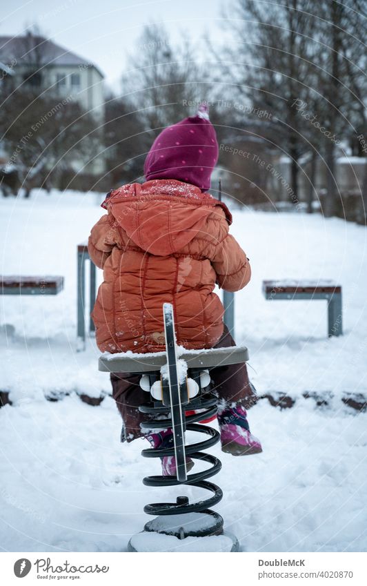 Ein Kind spielt auf dem verschneiten Spielplatz mit einem Wipptier Tag Außenaufnahme natürlich Tiefenunschärfe Leben Freude kalt kalte jahreszeit Schnee